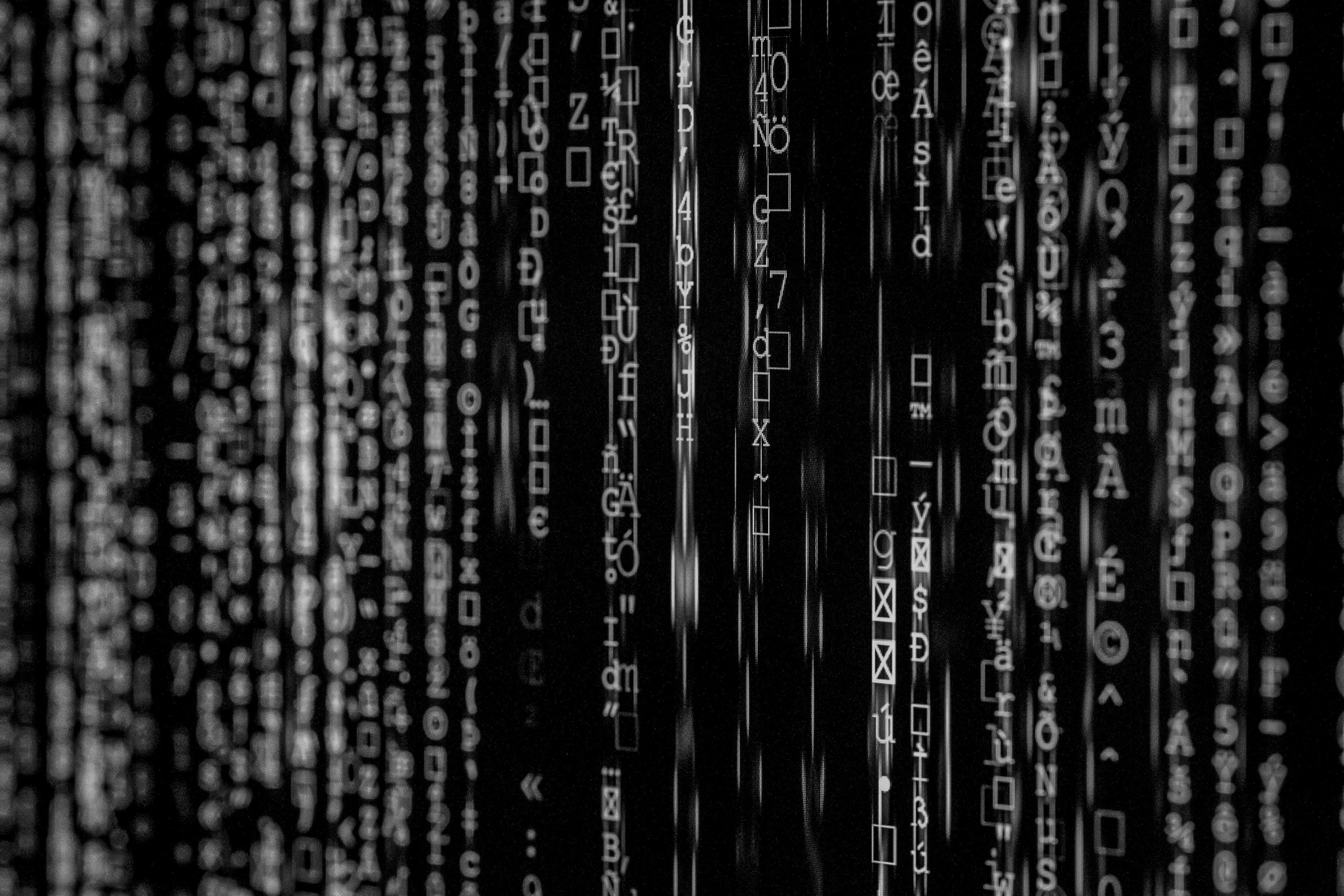 Black and white photo of vertical lines of abstract symbols and characters, resembling computer code.