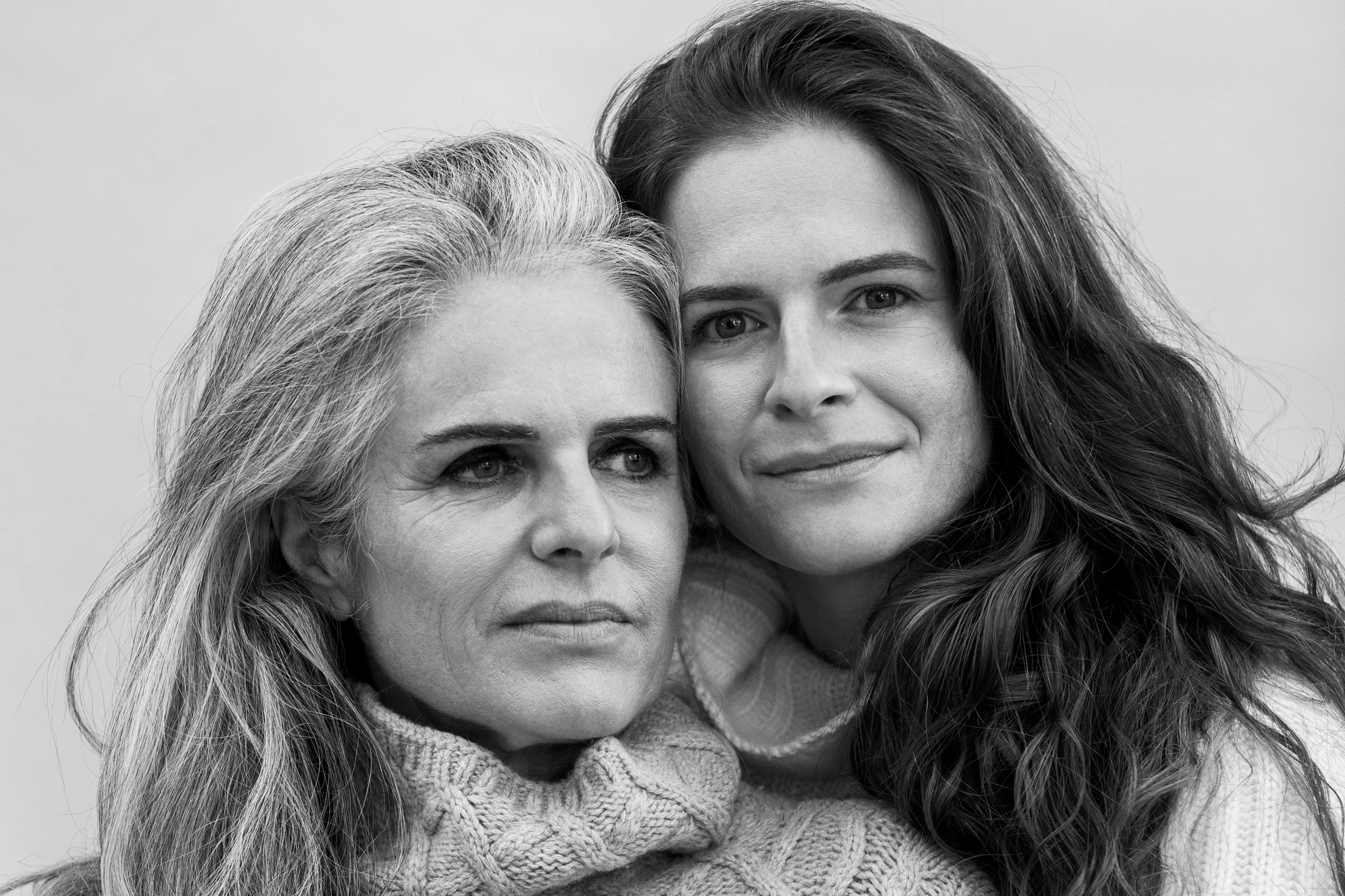 Monochrome portrait of a mother and daughter close together, wearing warm knits, sharing a bond