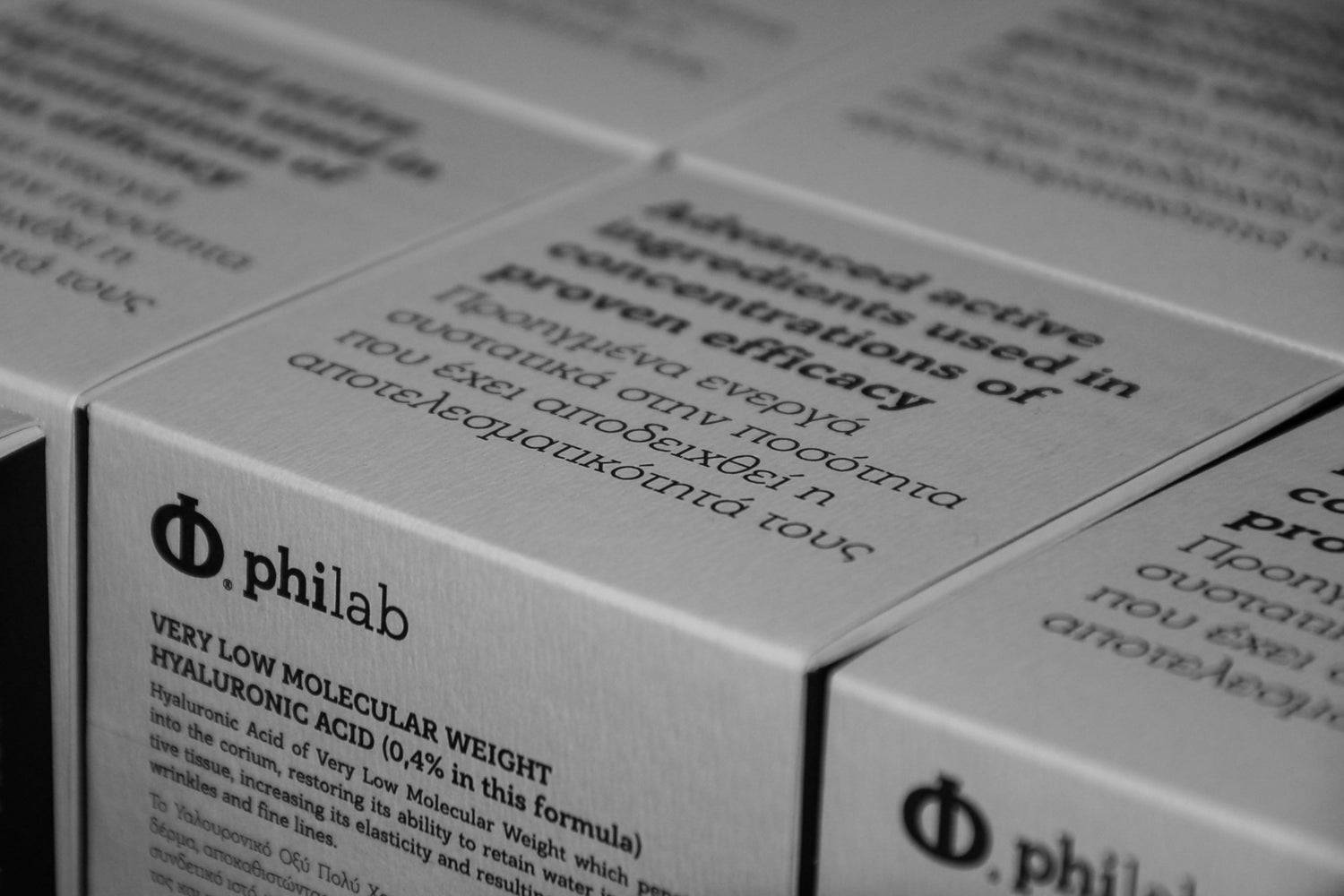 "Stack of Philab skincare boxes with detailed product information, focused in monochrome.