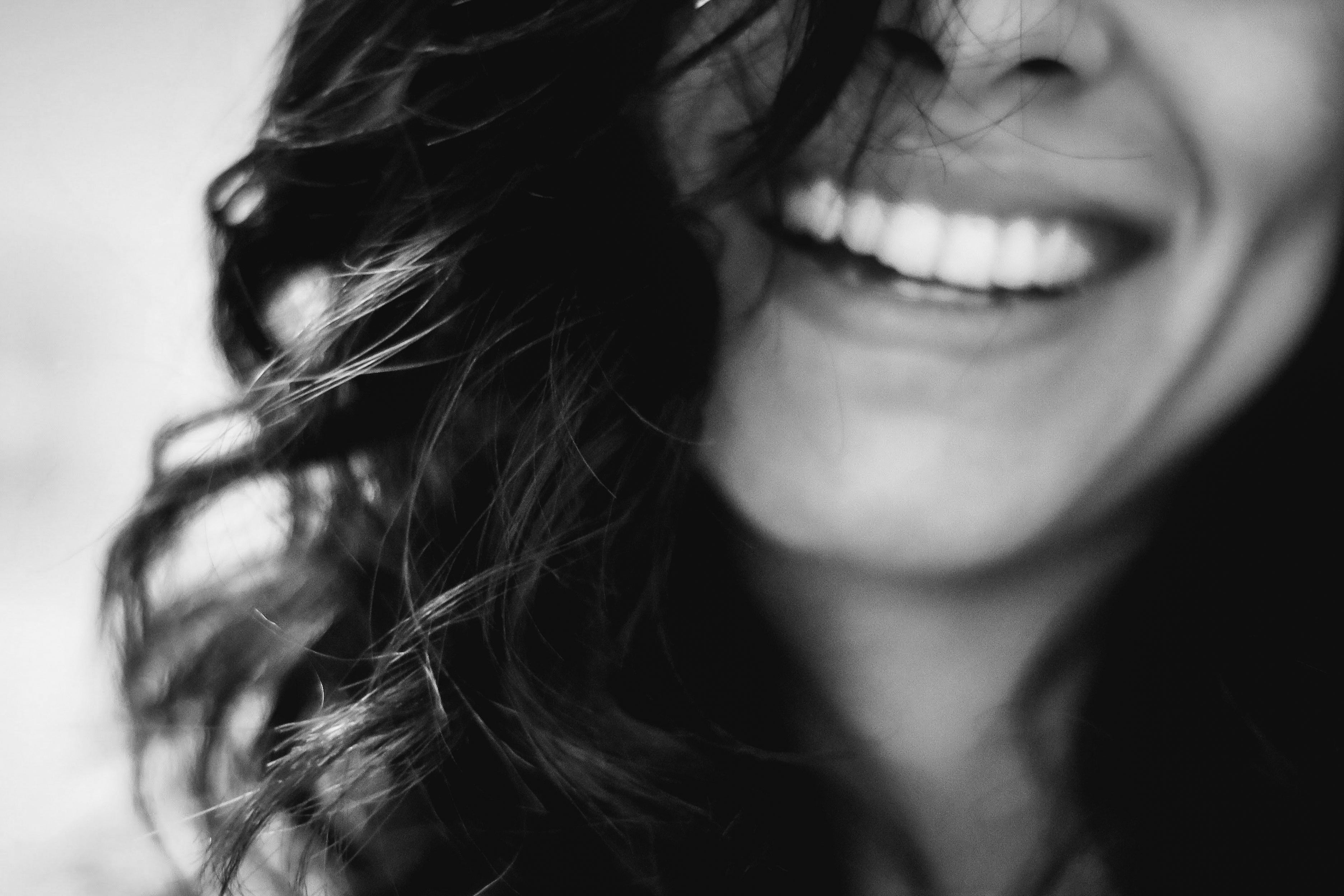 Close-up of a joyous woman smiling broadly, her curly hair framing the shot.