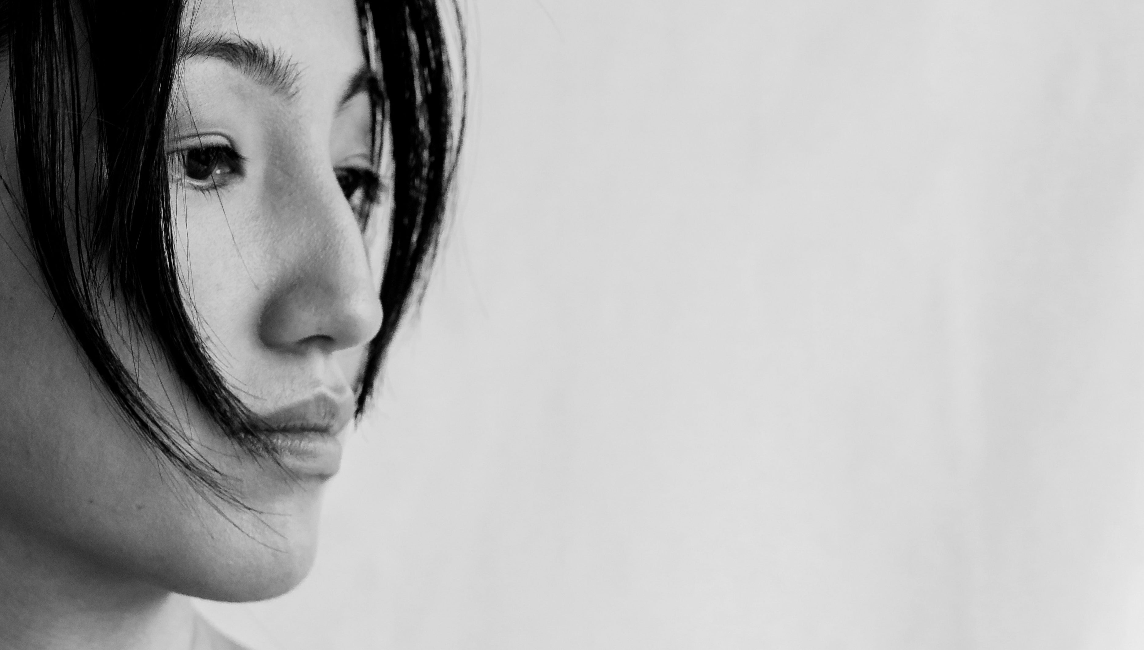 Close-up of a woman's contemplative face in monochrome, strands of hair framing her cheek.